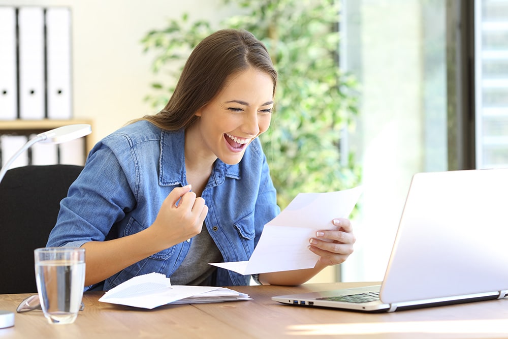 Excited woman reading acceptance letter in a desktop at office