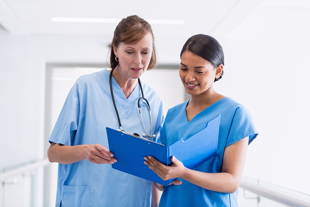 Nurse and doctor discussing over clipboard